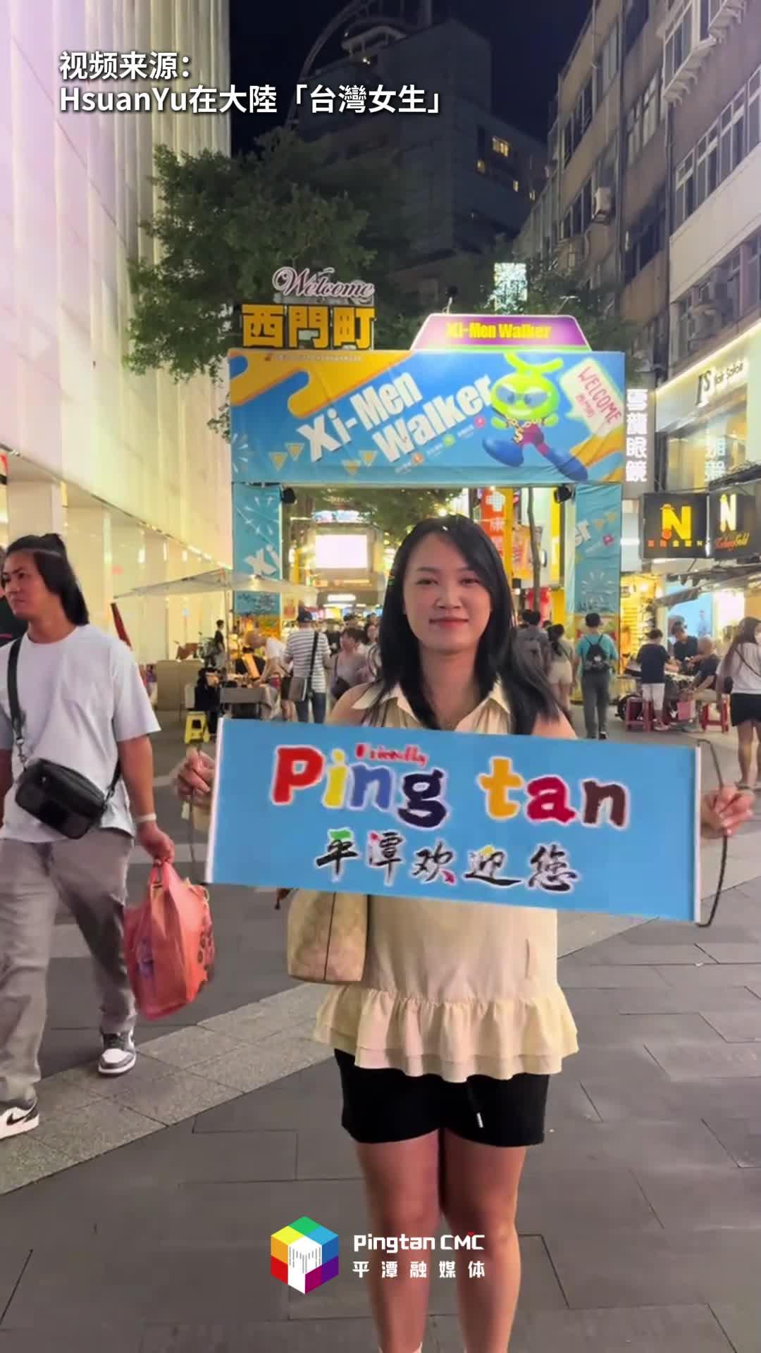 臺(tái)灣女生在臺(tái)灣街頭手舉條幅，歡迎五湖四海的朋友們來(lái)平潭做客！